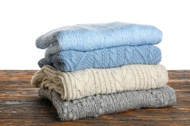 Ahşap masada beyaz arka planda mavi ve gri süveterler