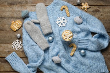 Şık bir kazak, eldiven, Noel süsü, kakaolu bir fincan ve ahşap arka planda marşmelov.