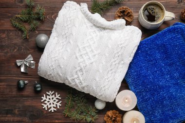 Şık kazaklar, bir fincan kahve, yanan mumlar ve ahşap arka planda Noel dekoru, yakın plan.