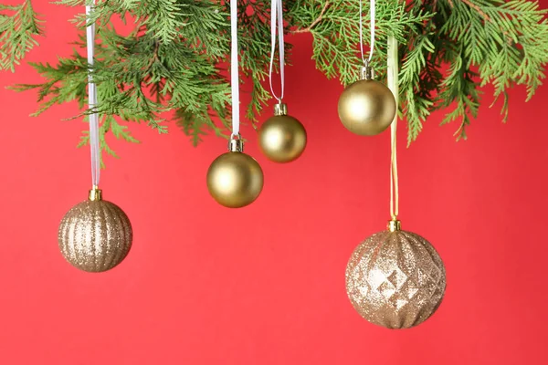 Goldene Weihnachtskugeln Hängen Thuja Zweigen Vor Rotem Hintergrund — Stockfoto
