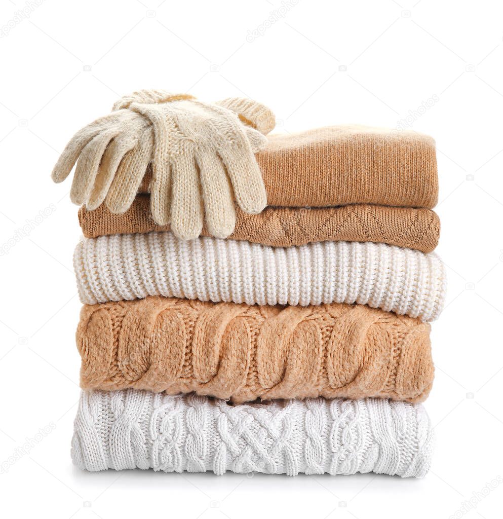 Different stylish sweaters and gloves on white background