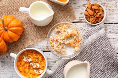 Beyaz ahşap arka planda balkabağı ve bir kase lezzetli yulaf ezmesi.