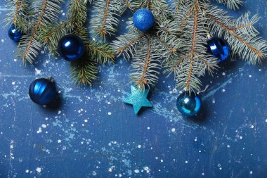 Mavi arka planda topları ve köknar dalları olan Noel kompozisyonu