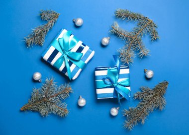 Mavi arka planda hediye kutuları, toplar ve köknar dallarıyla Noel kompozisyonu