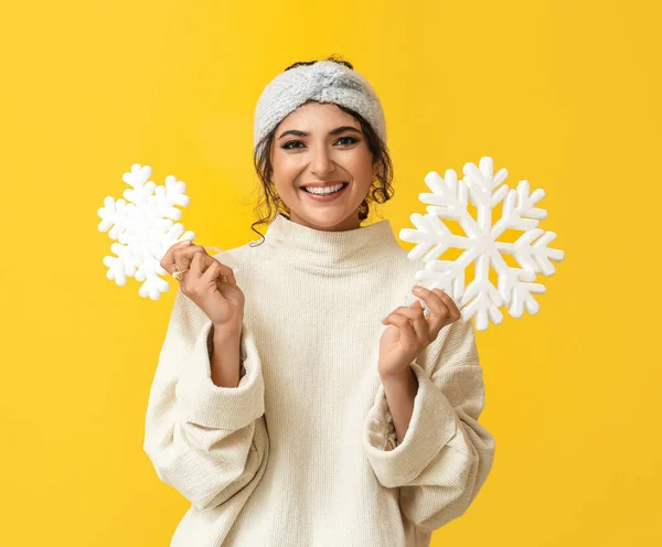 黄色の背景に大きな雪片を保持する美しい女性 — ストック写真