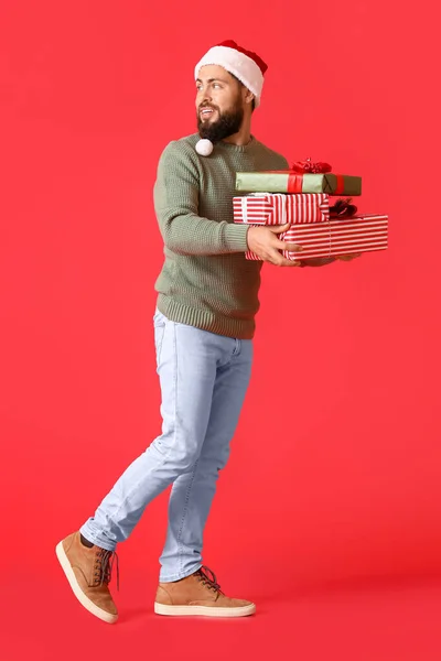 Gehender Mann Mit Weihnachtsgeschenken Auf Farbigem Hintergrund — Stockfoto