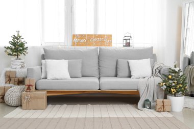 Küçük Noel ağaçları ve kanepesi olan aydınlık oturma odasının içinde.