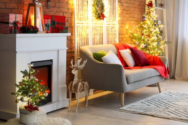 Şık oturma odasının içinde şöminesi, Noel ağaçları ve parlayan ışıkları var.
