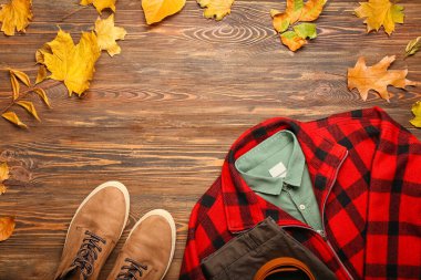 Şık ekose ceket, gömlek, pantolon, kemer, ayakkabı ve ahşap arka planda sonbahar yaprakları.