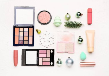 Beyaz arka planda Noel dekoru olan makyaj malzemeleri.