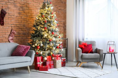Rahat bir kanepe, koltuk ve odasındaki tuğla duvarın yanındaki Noel ağacı.
