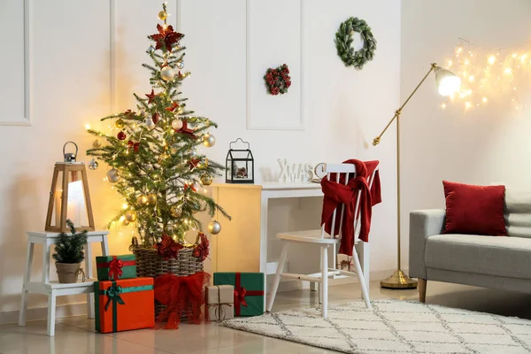 Interior of light room with modern workplace, Christmas tree and glowing lights