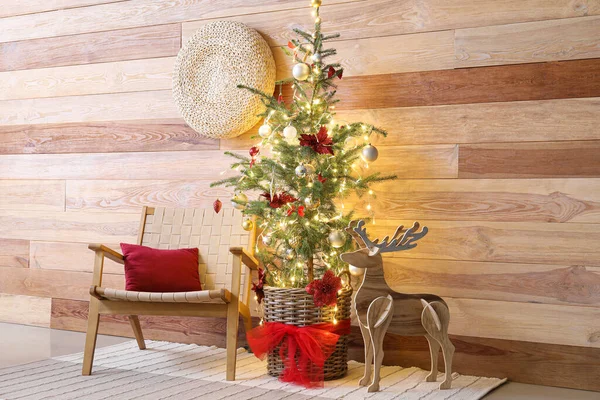 木製の壁の近くに輝くライト アームチェア トナカイとクリスマスツリー — ストック写真