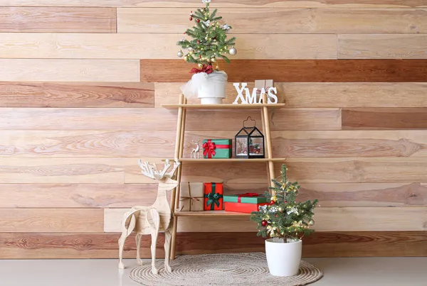 木製の壁の近くにギフト 小さなクリスマスツリーやトナカイと棚ユニット — ストック写真