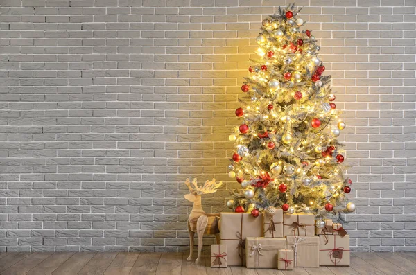 Gyönyörű Karácsonyfa Izzó Fények Ajándékok Rénszarvas Közelében Téglafal — Stock Fotó