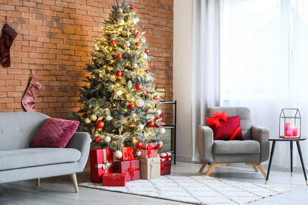 Rahat bir kanepe, koltuk ve odasındaki tuğla duvarın yanındaki Noel ağacı.