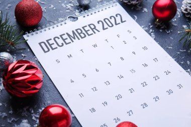 Aralık 2022 için kağıt takvim ve karanlık masa üzerinde Noel dekoru, yakın plan