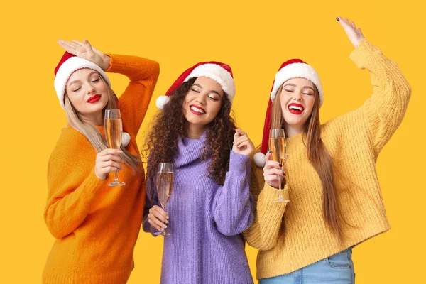 Schöne Junge Frauen Nikolausmützen Und Mit Champagnergläsern Auf Farbigem Hintergrund — Stockfoto