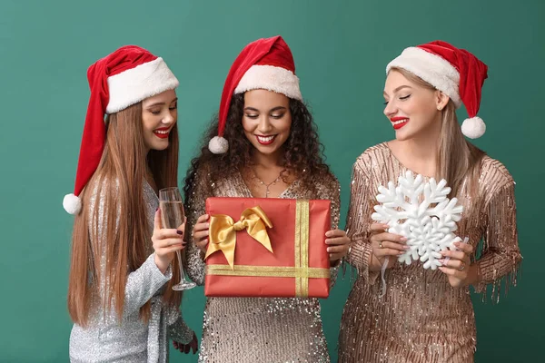 Schöne Junge Frauen Weihnachtsmützen Mit Weihnachtsgeschenk Und Champagner Auf Farbigem — Stockfoto