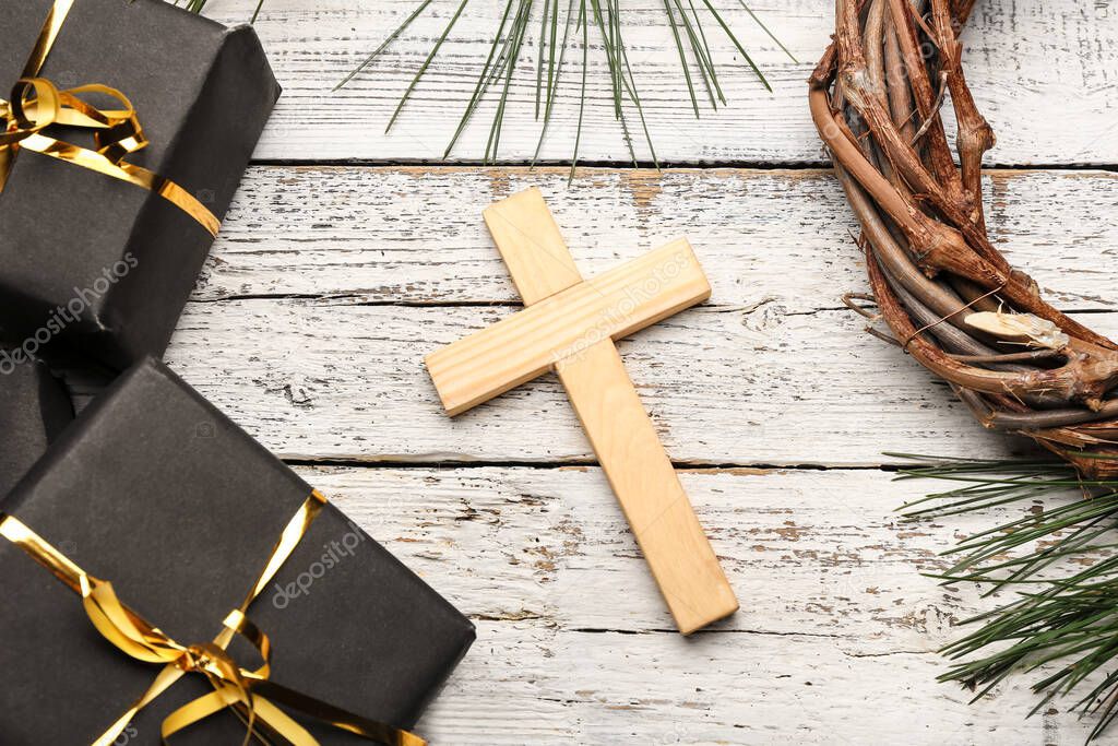 Cross with wreath and gifts on white wooden background. Concept of Christmas story