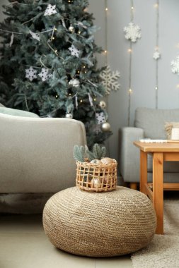 İçinde Noel dekoru olan sepet oturma odasında pouf üzerine.