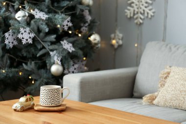 Bardak ve oyuncak araba, Noel için dekore edilmiş oturma odasındaki ahşap masada.