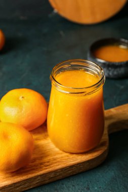 Koyu arkaplanda lezzetli mandalina reçeli kavanozu, yakın plan.