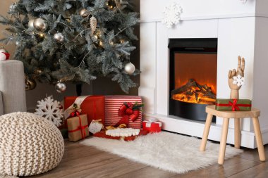 Noel ağacının altındaki hediye kutuları oturma odasındaki şöminenin yanında.