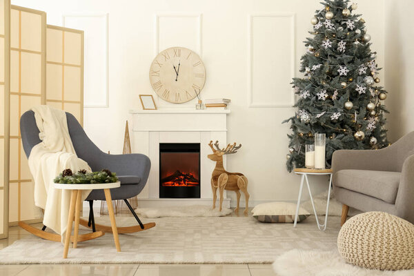 Interior of light living room with Christmas tree and reindeer near fireplace