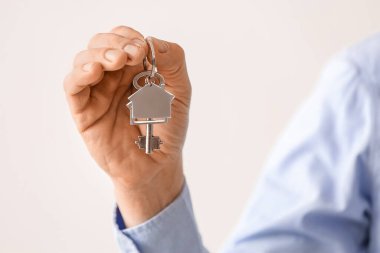 Işıklı arka planda evden anahtarı tutan adam, yakın plan