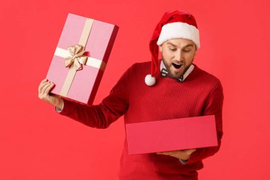Şaşırdım genç adam Noel hediyesini renk arka planıyla açıyor.