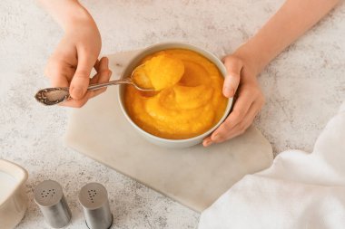 Hafif arka planda balkabağı kremalı çorba içen kadın