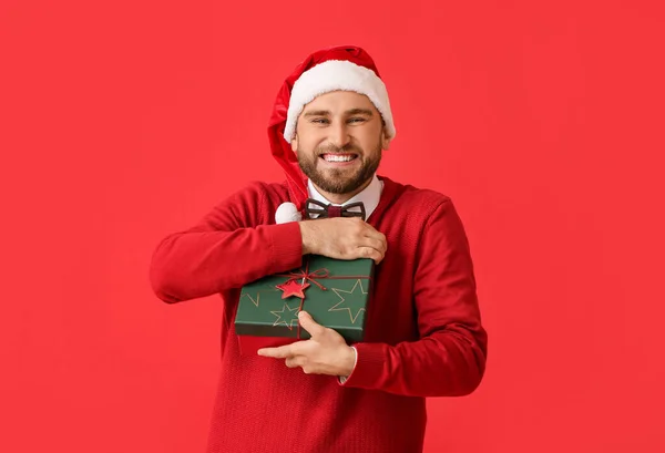 Glücklicher Junger Mann Mit Weihnachtsgeschenk Auf Farbigem Hintergrund — Stockfoto