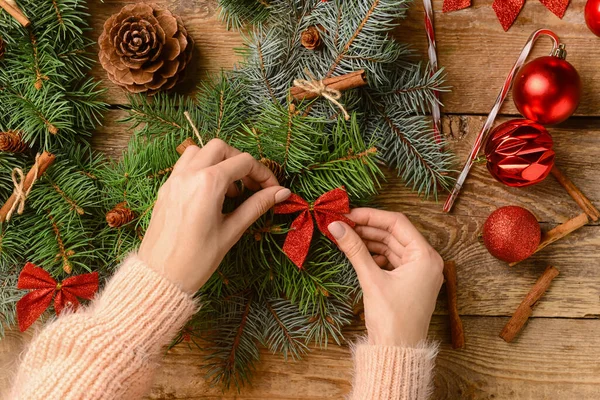 Vrouw Versieren Kerstkrans Gemaakt Van Sparren Takken Houten Achtergrond — Stockfoto