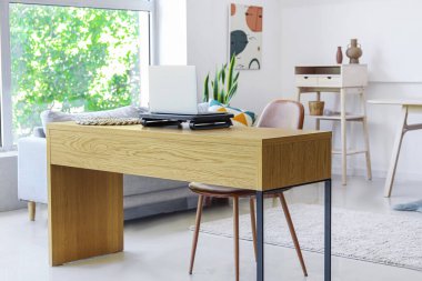 Modern odada dizüstü bilgisayarı ve sandalyesi olan ahşap masa.