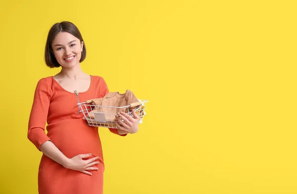 Ung Gravid Kvinna Som Håller Korg Med Babykläder Gul Bakgrund — Stockfoto