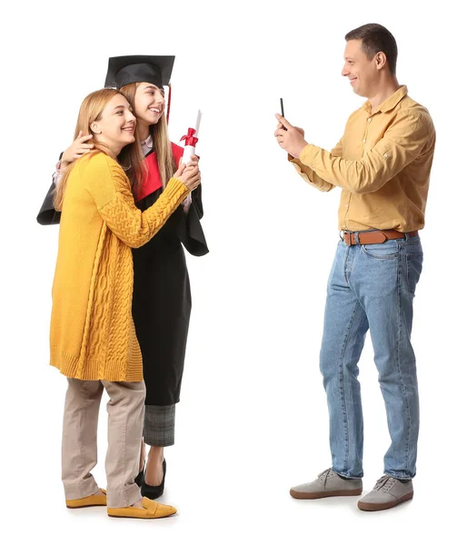 快乐的男人为他的妻子和女儿拍了照 他们穿着毕业礼服 拿着白底文凭 — 图库照片