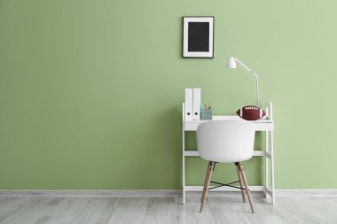 Yeşil duvarın yanında klasörleri ve rugby topu olan modern işyeri