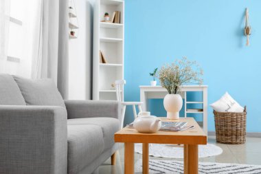 Gri kanepeli ve ahşap masalı aydınlık oturma odasının içi.