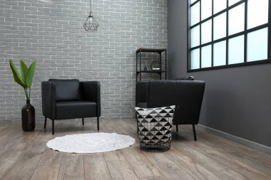 Modern oturma odasının içindeki siyah koltuklar.