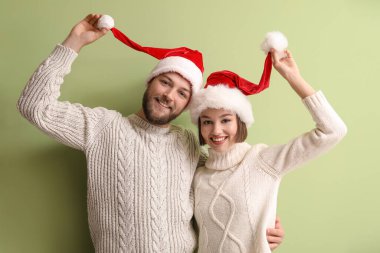 Şık kış kıyafetleri ve renkli Noel Baba şapkaları giyen mutlu genç çift.