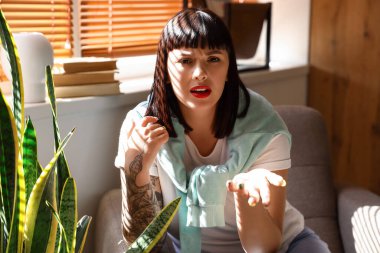 Dövmeli genç kadın evde video sohbeti yapıyor.