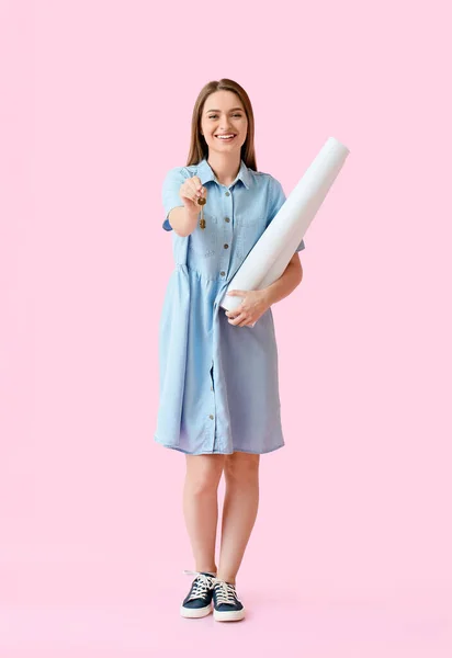 Lächelnde Junge Frau Mit Hausschlüssel Und Papierrollen Auf Rosa Hintergrund — Stockfoto