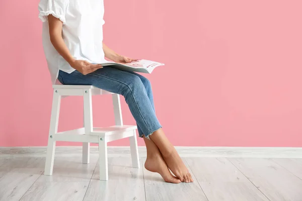 Frau Liest Magazin Auf Weißem Stufenhocker Nahe Rosa Wand — Stockfoto