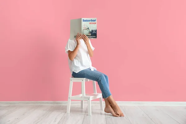 Pembe Duvarın Yanındaki Beyaz Taburede Dergi Okuyan Kadın — Stok fotoğraf
