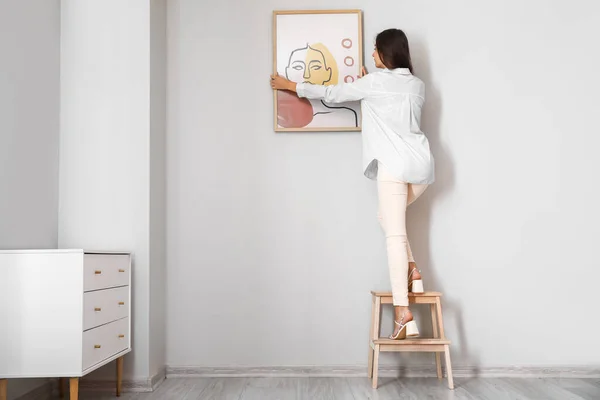 Woman Stepladder Hanging Painting Light Wall — Stock Photo, Image