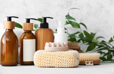 Banyo süngeri, masaj sabunu ve açık arkaplanda duran kozmetik ürünler.
