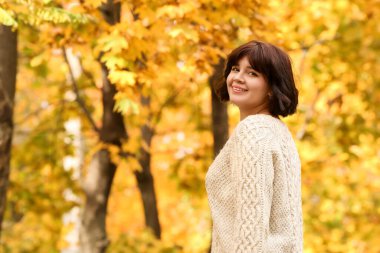 Mutlu esmer kadın sonbahar parkında güneşli bir günün tadını çıkarıyor.