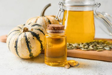 Işık arka planında kabak tohumu yağı olan şişe ve kavanoz.