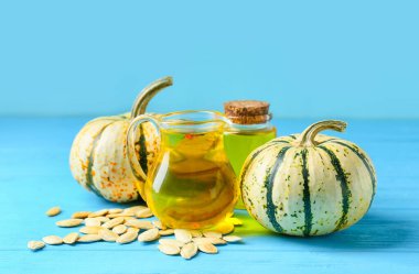 Mavi arka planda balkabağı tohumu yağı olan sürahi ve şişe.